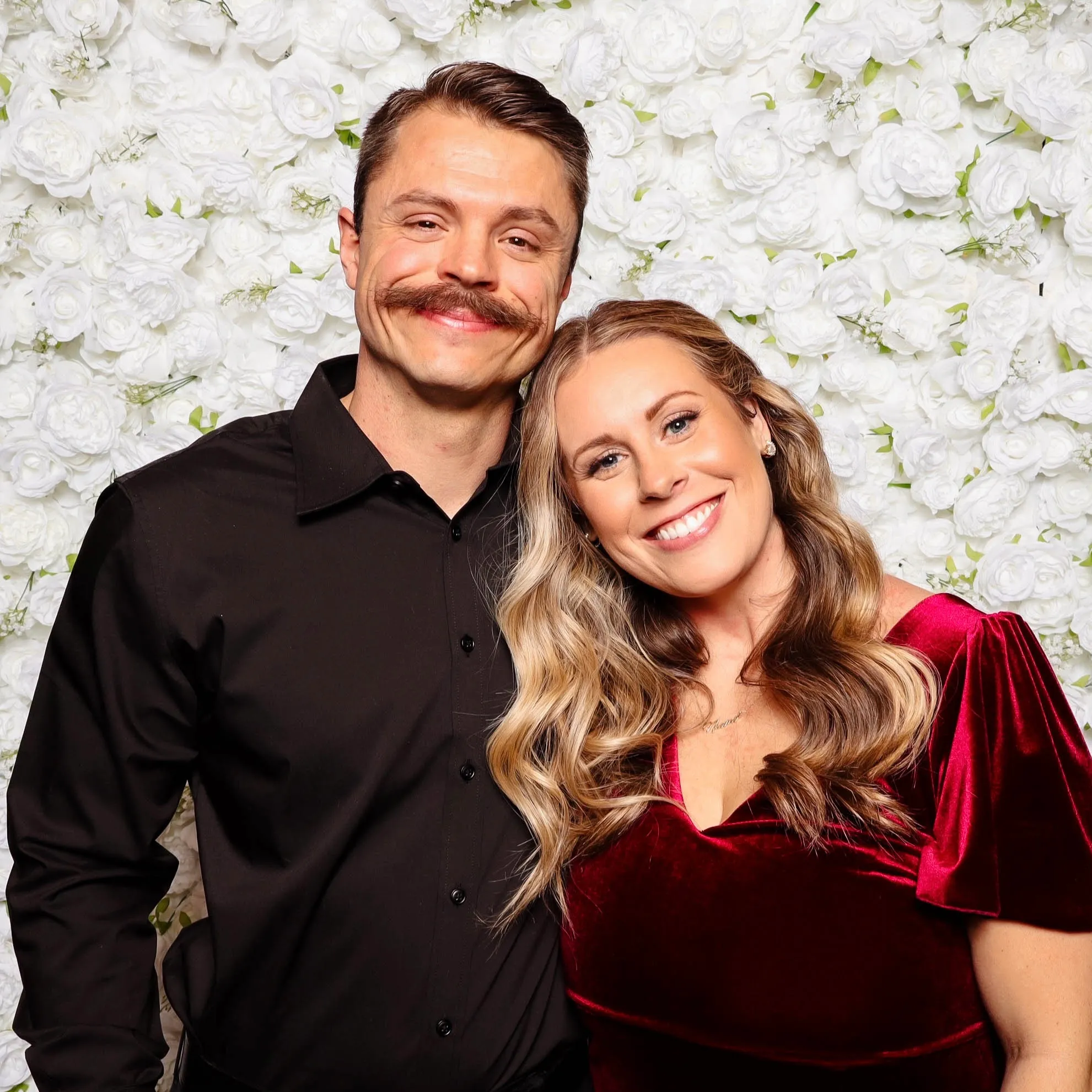 Couple at a wedding photo booth posing in front of a flower wall photo booth backdrop in Portland