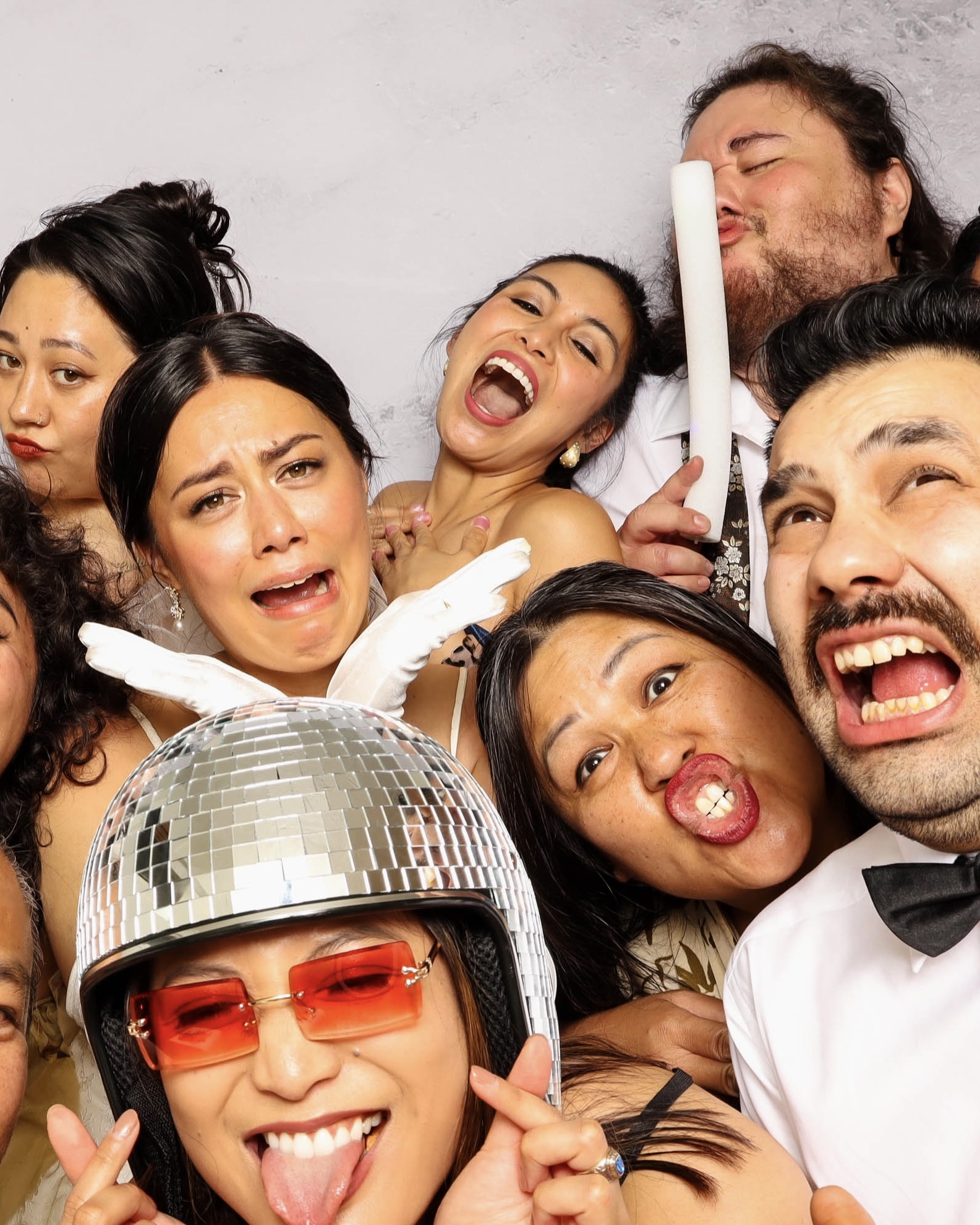 Group of diverse people making funny and playful faces during a festive photo booth session.