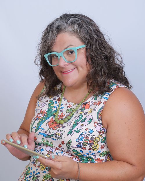 Emily is holding a ipad while wearing a bug patterned dress.