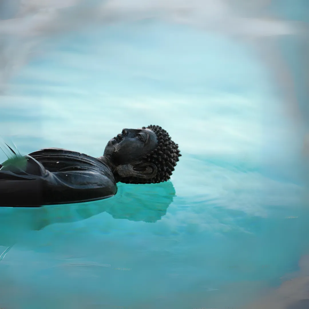 a statue of buddha lying peacefully on a calm blue lake