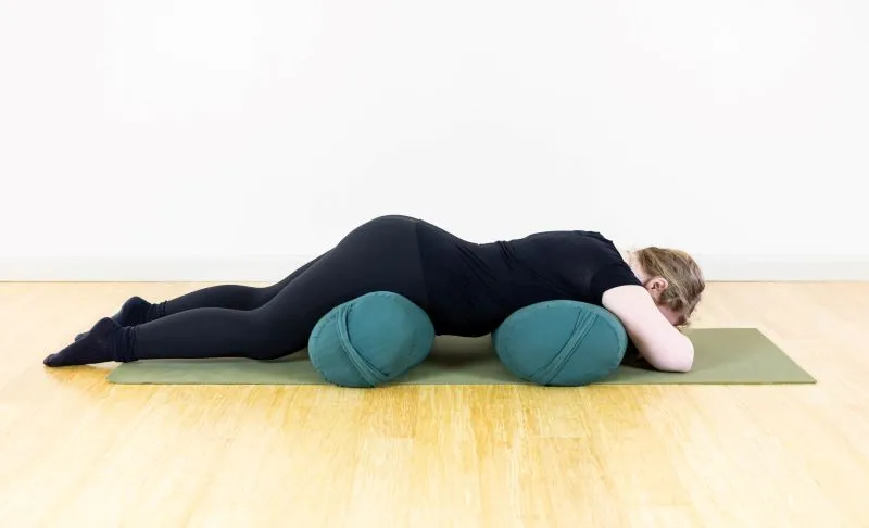 female yoga belly-lying on top of two yoga bolsters