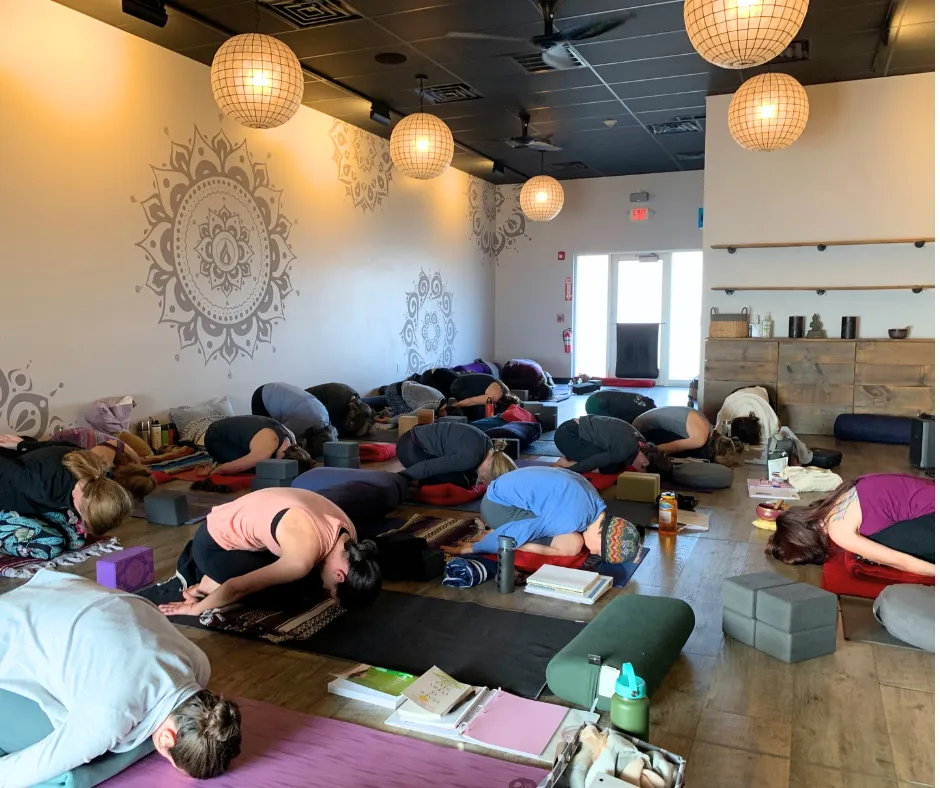 yoga students in child's pose in a yoga studio