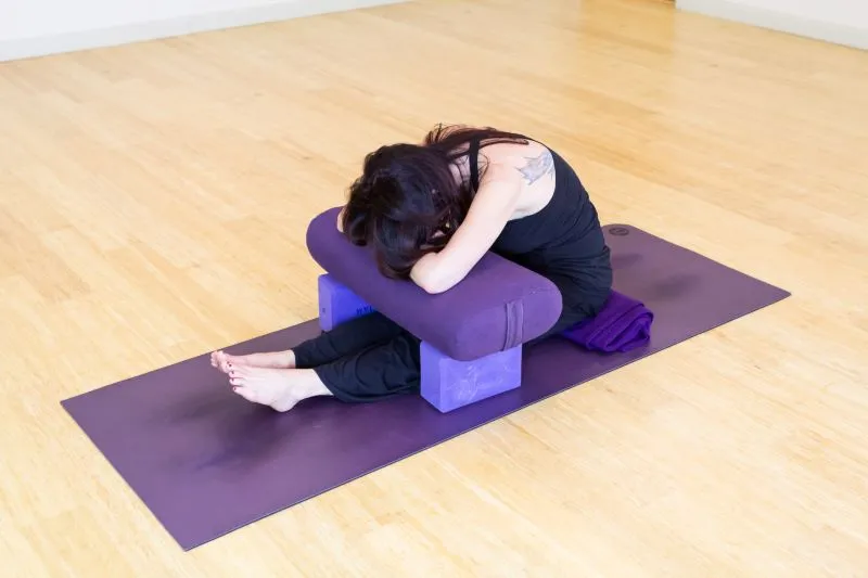 a female yoga practitioner doing Caterpillar pose on a yoga mat in a studio