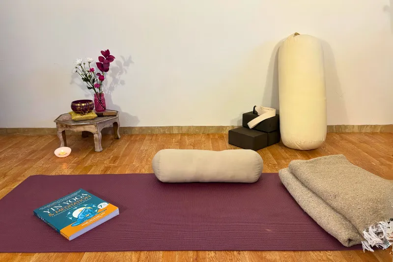 a peaceful yoga studio with mat, candles, props, and flowers