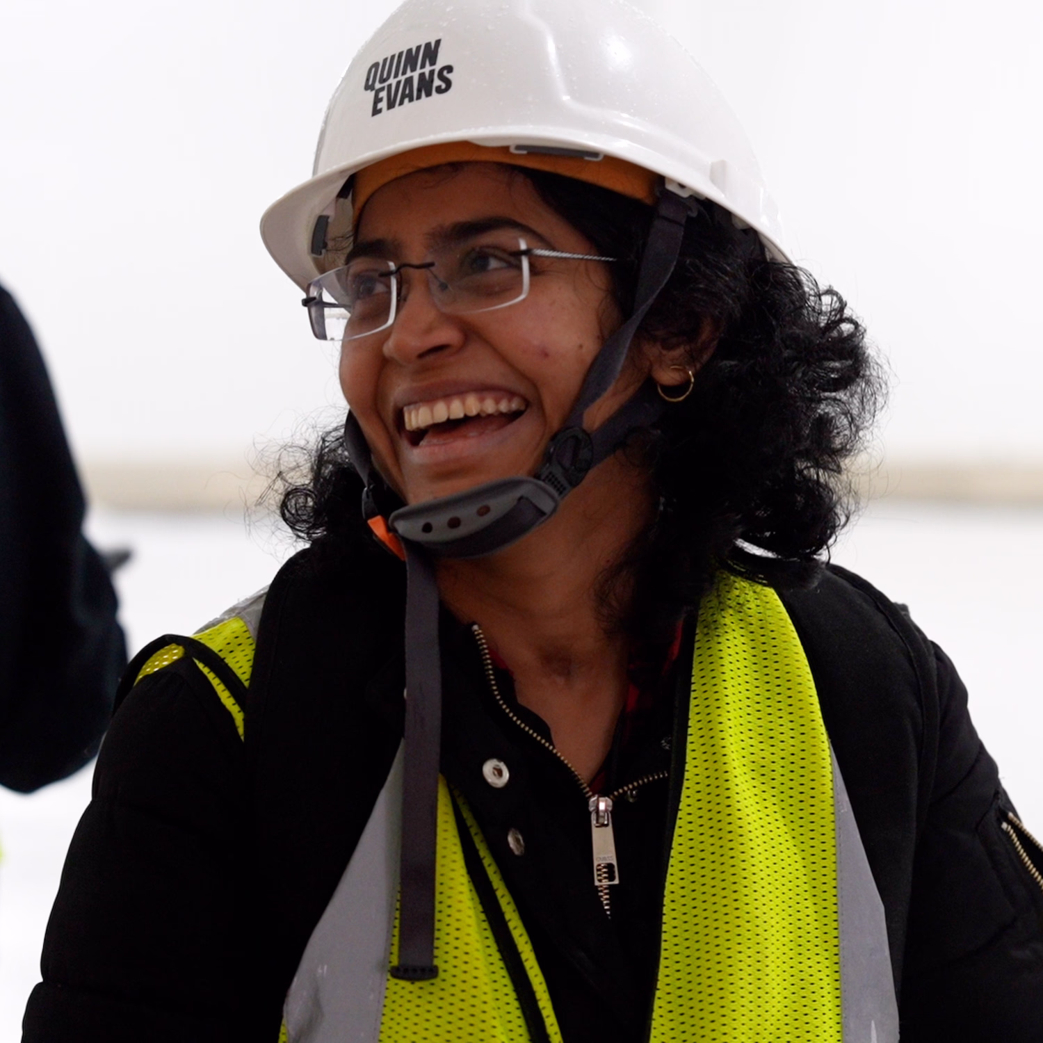 A team member wears a hard hat and vest on site.