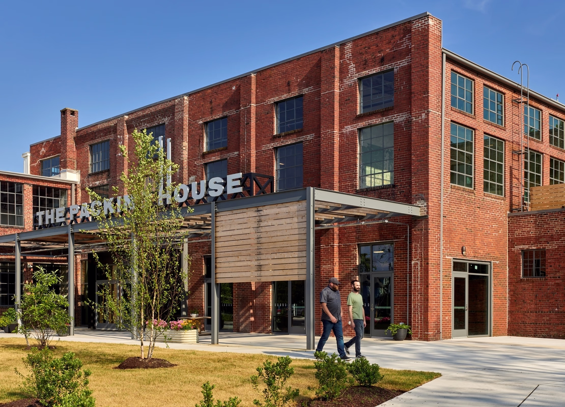 A repurposed factory building is enjoyed by visitors on a bright day.