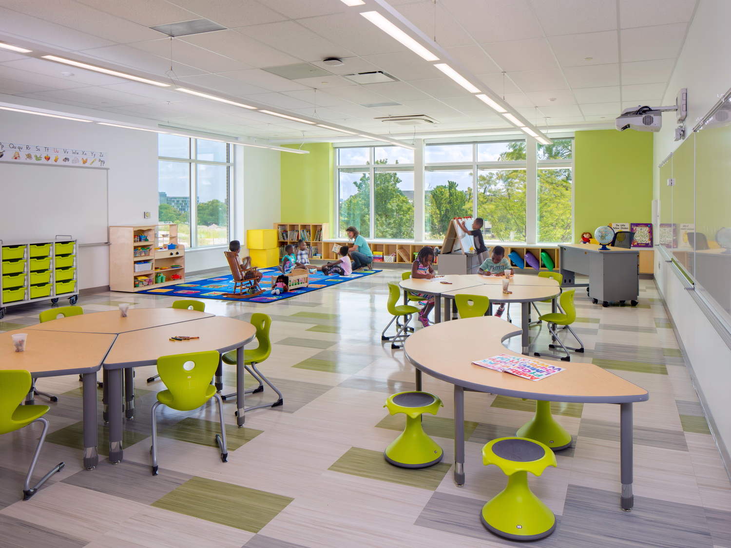 Students engage in indoor classroom activities near large windows.
