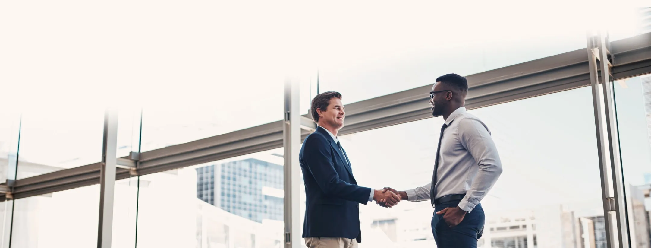 2 Business men shaking hands in an open indoor space