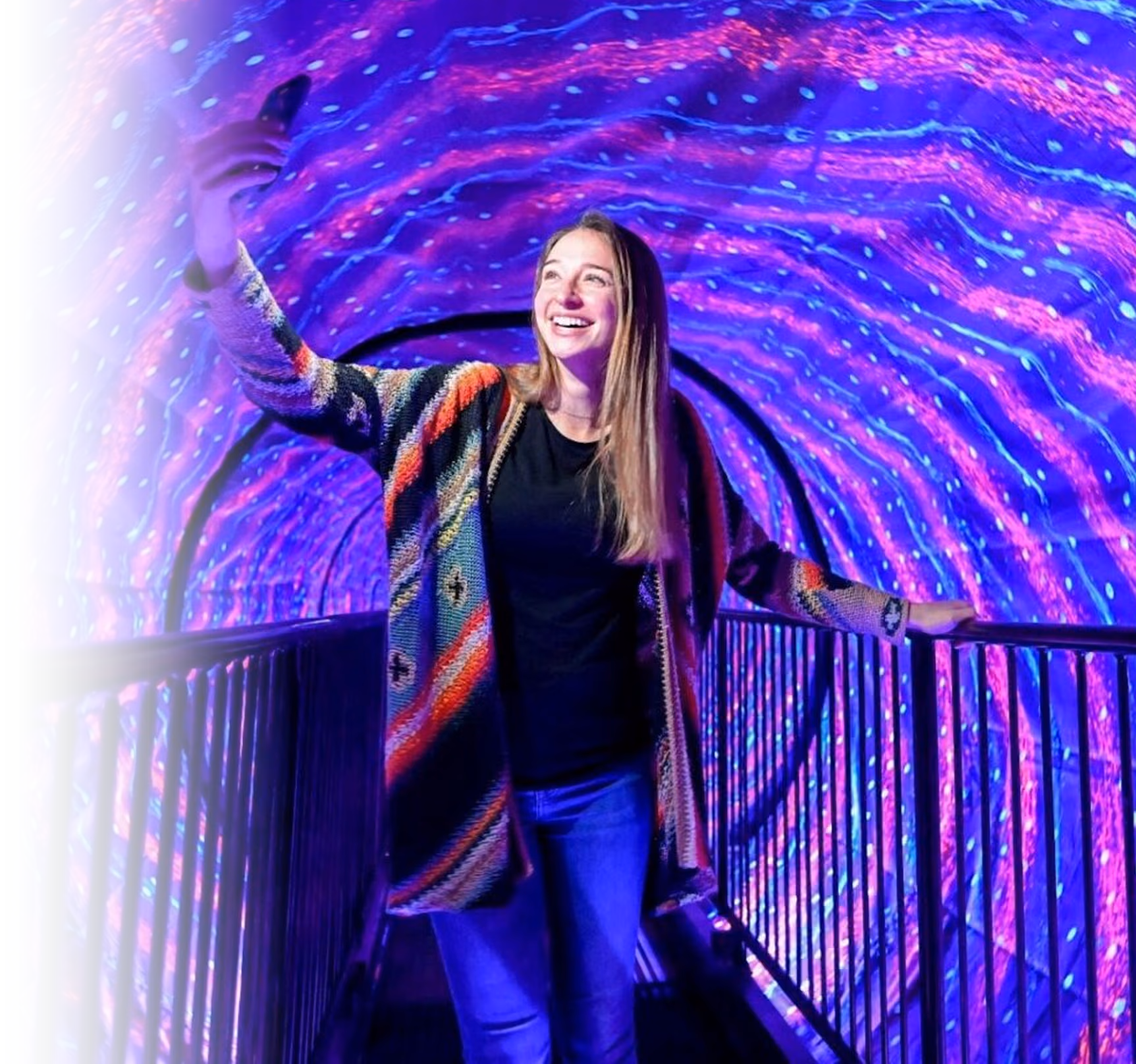 Smiling guest walking through a colorful LED light tunnel at an immersive attraction