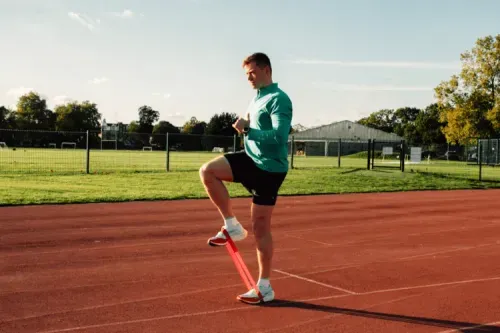 A man stretching on a running track.
