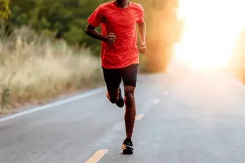 A man running down a road in a red shirt.