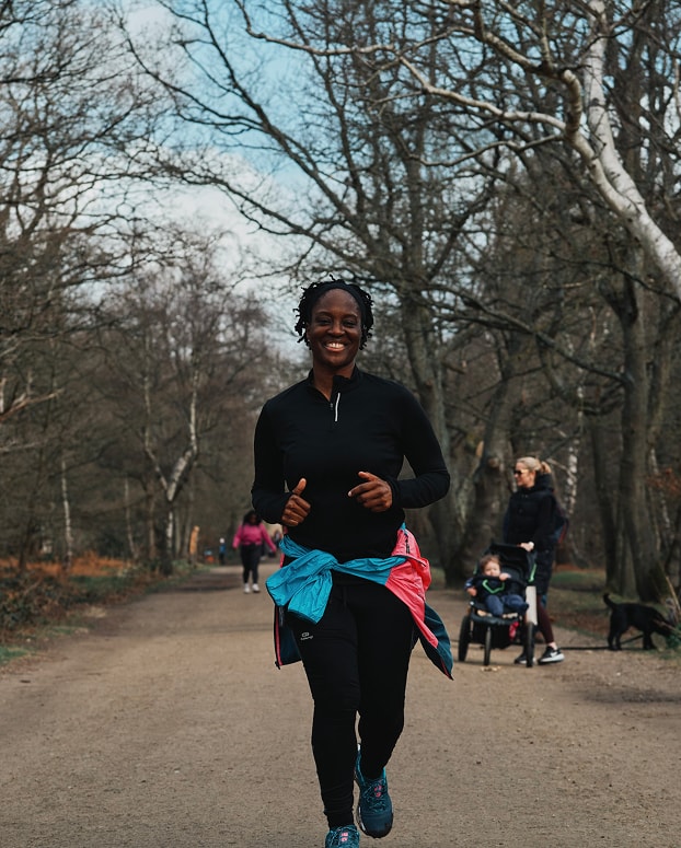 A woman running down a dirt road in a park.