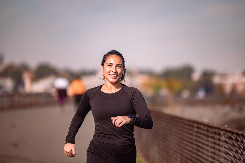 A woman is running on a path near a fence.