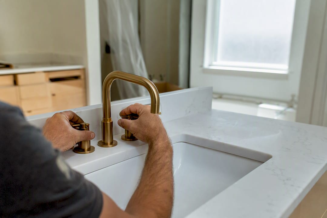 Hands installing faucet in bathroom remodel