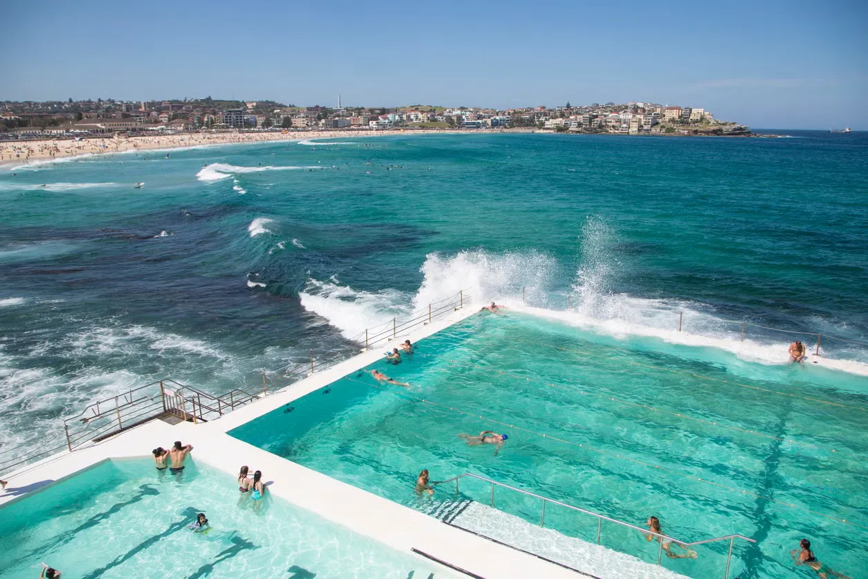 Turquoise outdoor pool at Bondi with swimmers and the sea beyond.