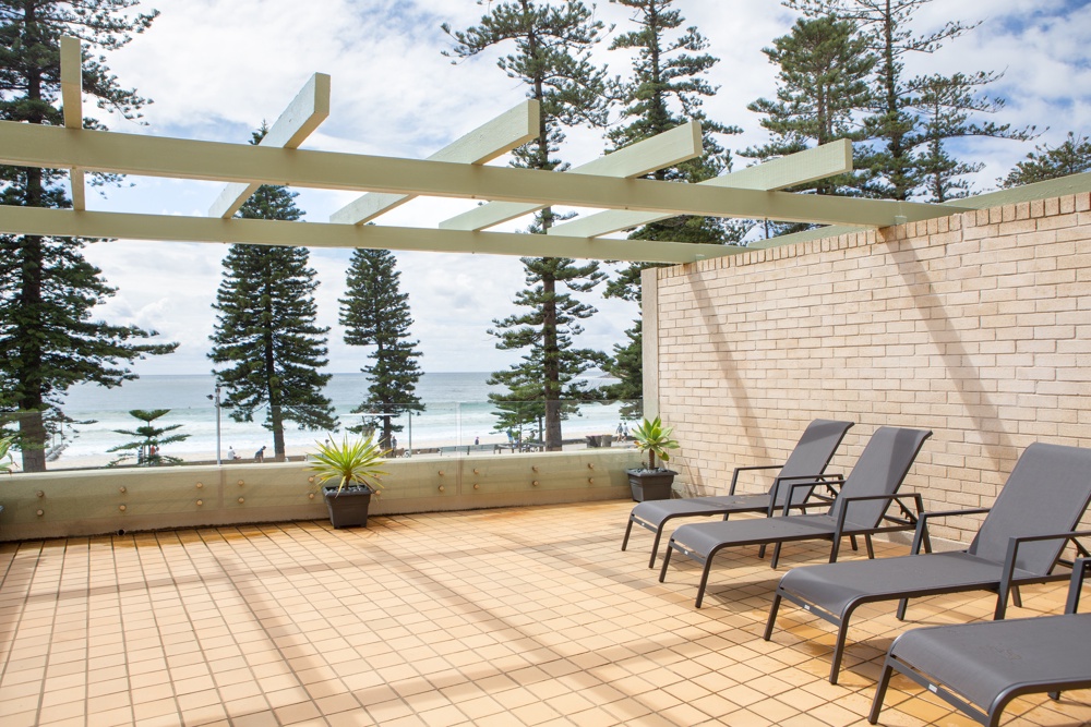 Manly apartment balcony with outdoor seating overlooking the beach