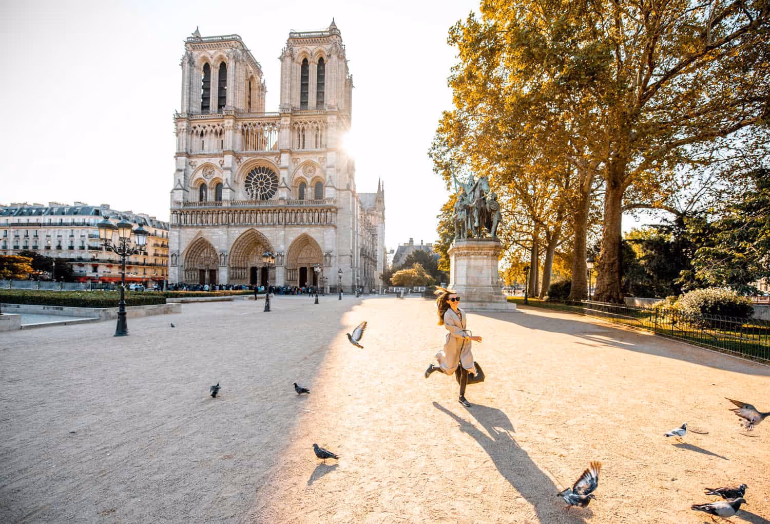 Woman running alone in front of Notre-dame with flying pigeons around - Dayin Guided Tours