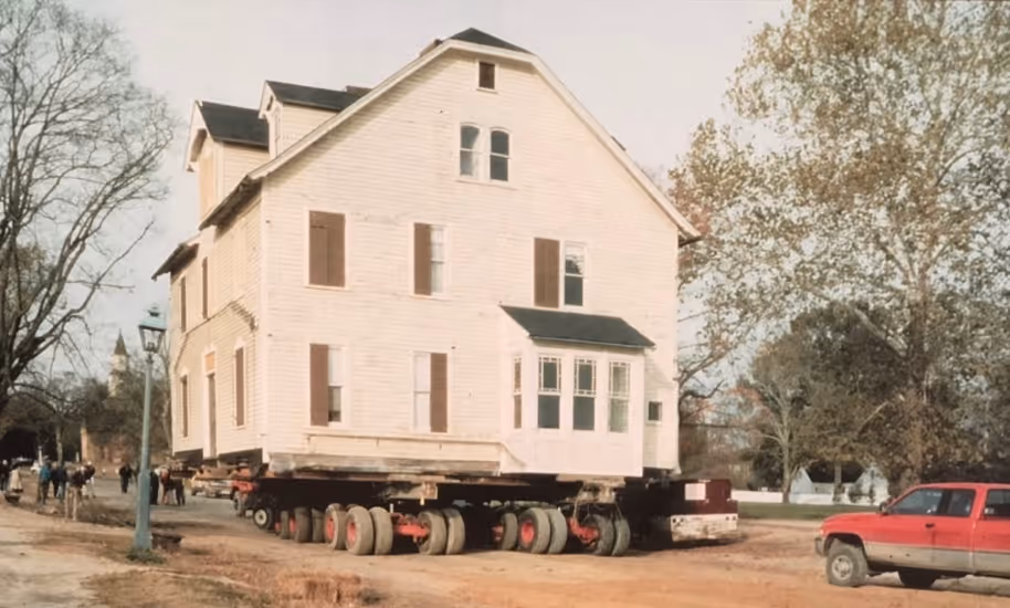 Side view of the Armistead House mounted on a heavy transport vehicle during the 1995 relocation from Duke of Gloucester Street, Williamsburg, Virginia