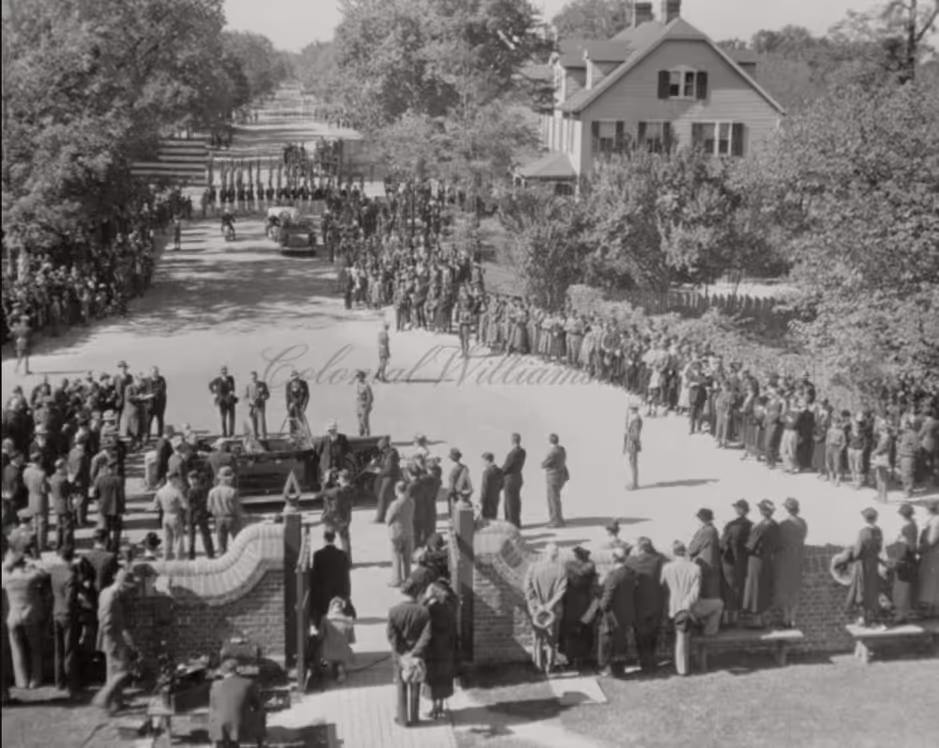 Aerial black and white photograph of a large public gathering on Duke of Gloucester Street in Colonial Williamsburg, Virginia in the 1930s, with the Armistead House visible at upper right