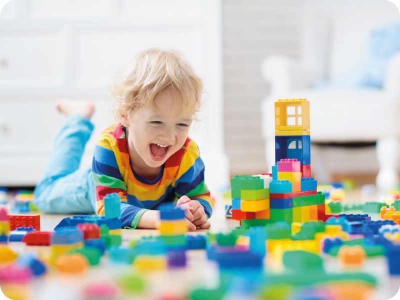 Niño pequeño sonriendo con juguetes didácticos.