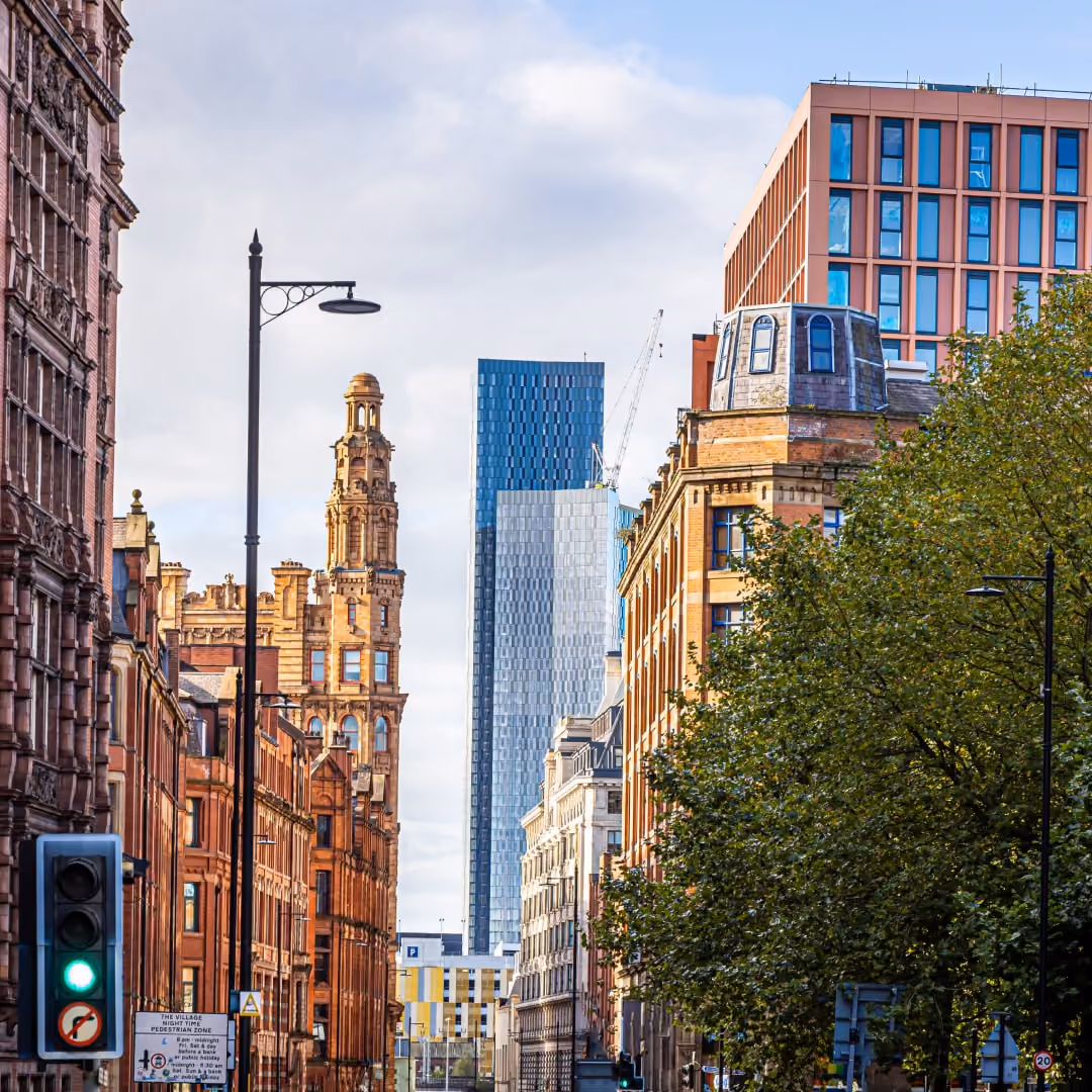 City street with historic brick buildings, a modern skyscraper in background, and green traffic light.