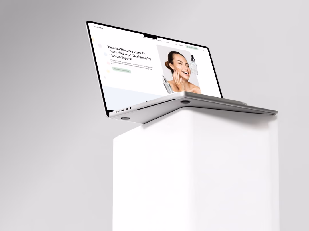 Open laptop on white pedestal showing a skincare website with a smiling woman and product images.