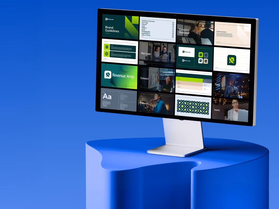 Curved computer monitor on blue table showing brand guideline slides for Revenue Amp.