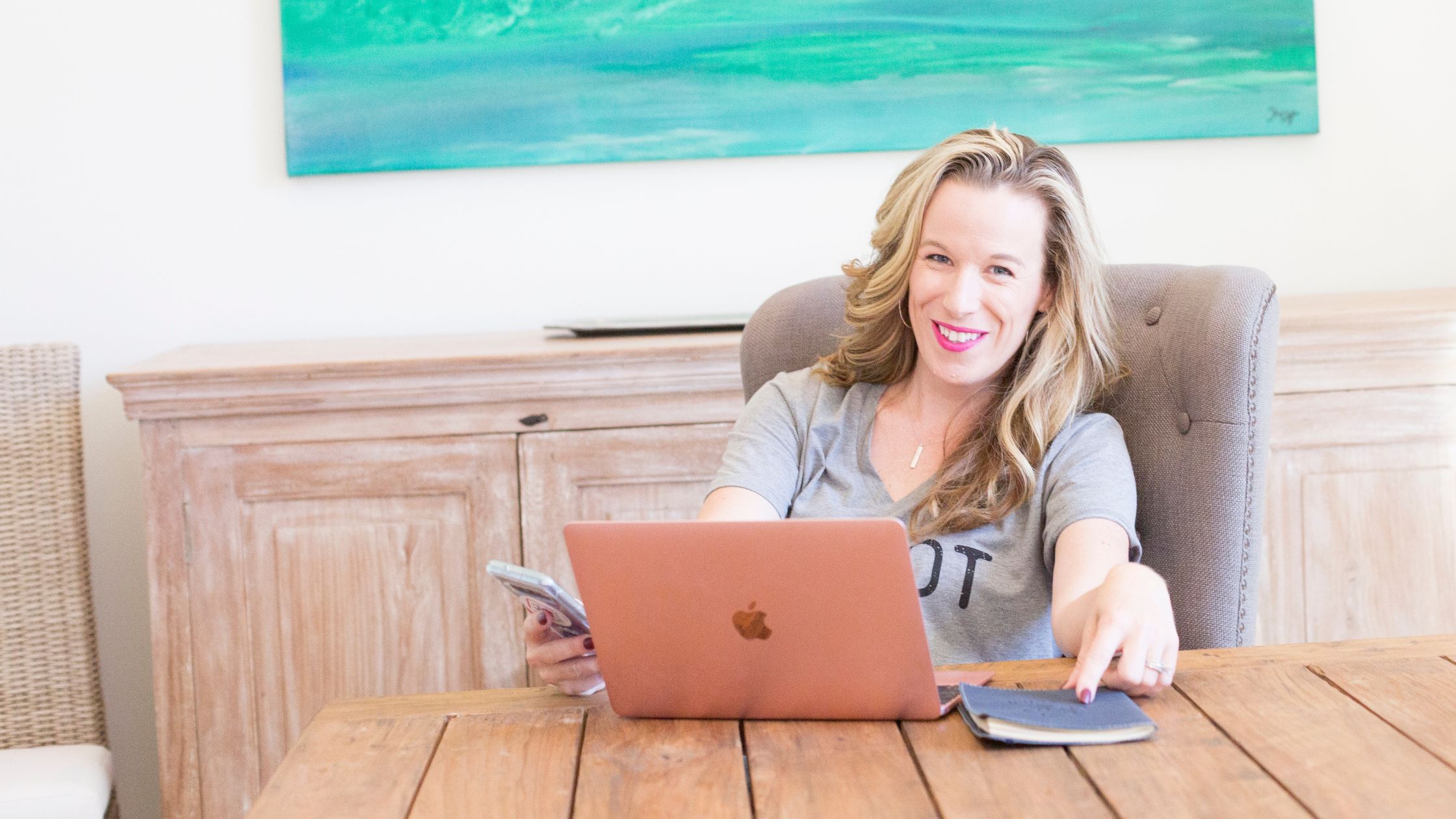 Woman sitting a table with a phone and laptop