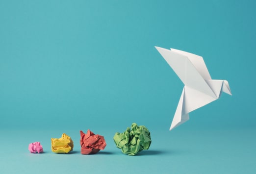 Four scrunched up paper balls followed by an origami bird against a blue background