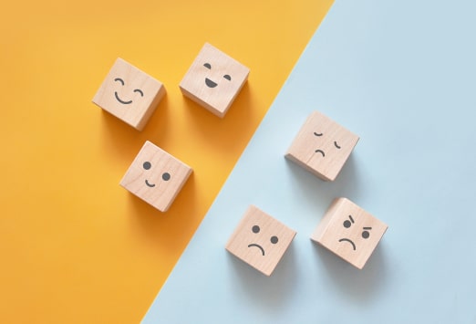 Wooden blocks with faces illustrating different emotions including sad, happy and angry