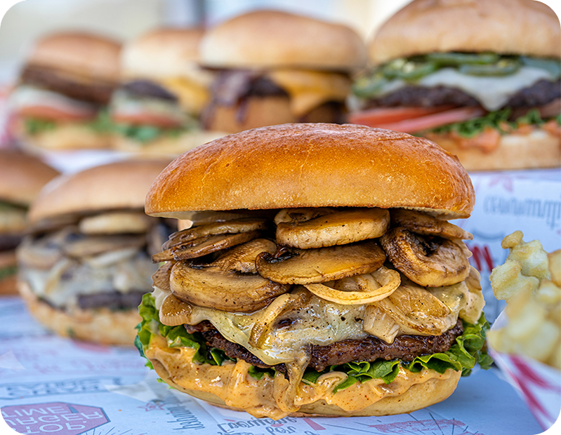 Cheeseburger with lettuce, tomato, onion, pickles, and melted cheddar cheese in a brioche bun, accompanied by 'Farm fresh not factory' and 'Halal' labels.