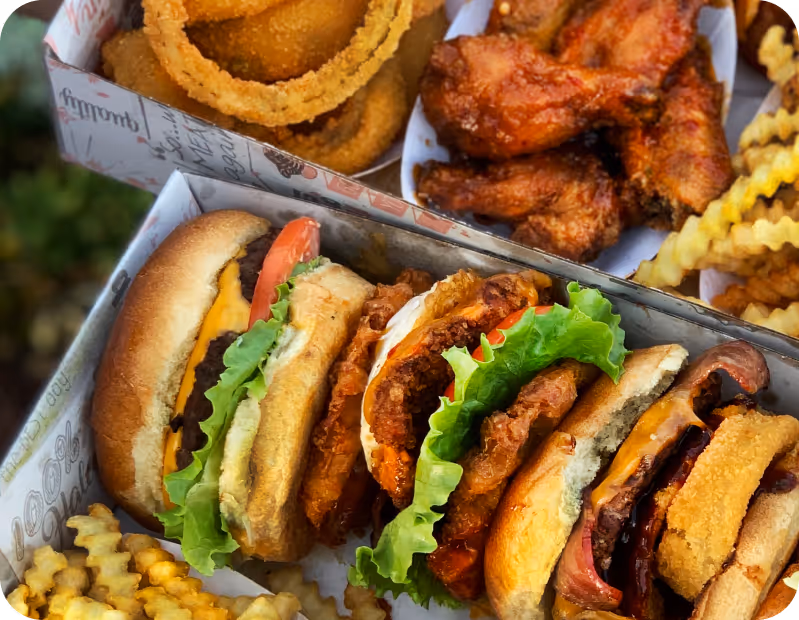 Trio of sandwiches with lettuce, tomato, fried chicken, cheese, and bacon served with crinkle-cut fries, onion rings, and chicken wings.
