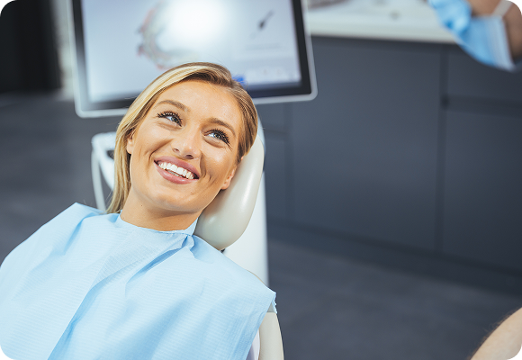 A girl sitting in a dental chair smiling at their dentist