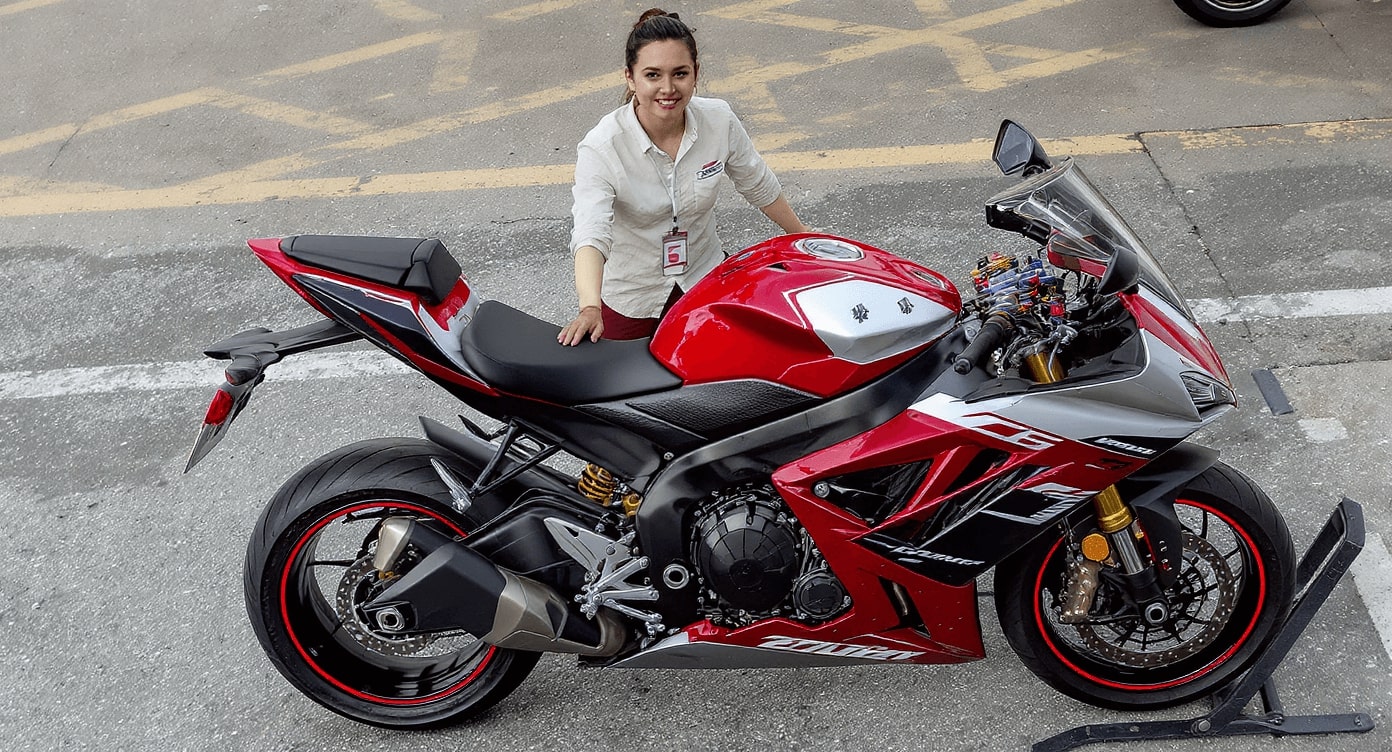 Frau steht neben rotem Motorrad