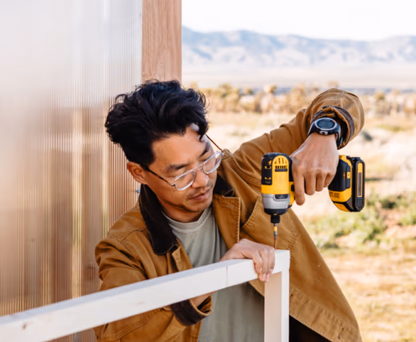 A Contractor using his drill to secure a frame.