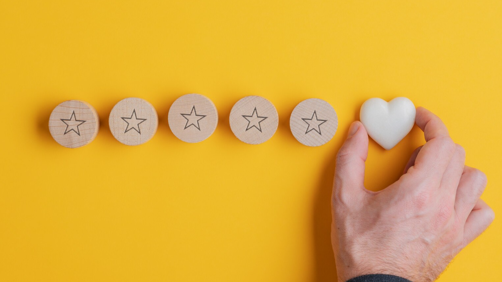 Hand placing a heart next to five stars, symbolizing customer loyalty, positive sentiment, and exceeding customer expectations.