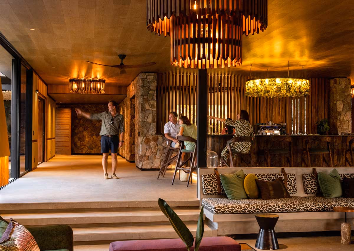 Indoor lounge with modern seating, two men and two women, warm lighting, and stone wall accents.