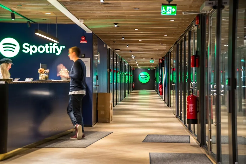 Gestão de desempenho: Área interna de um escritório do Spotify. É possível observar um corredor com o logo da empresa em destaque no final.