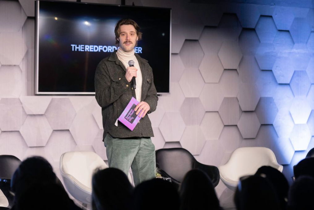 Man on stage with microphone speaking at event