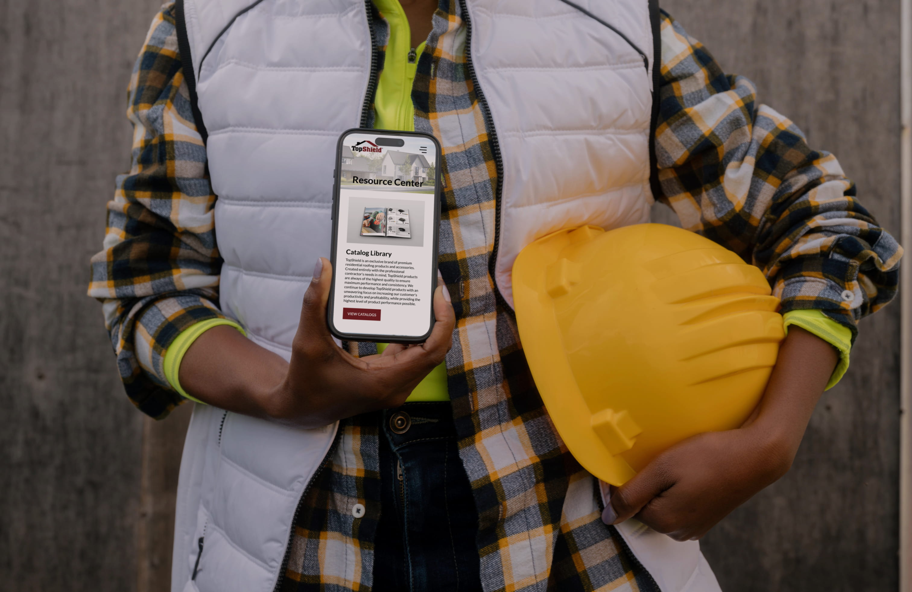 A construction worker holding a phone with the TopShield Resource Center page displayed.