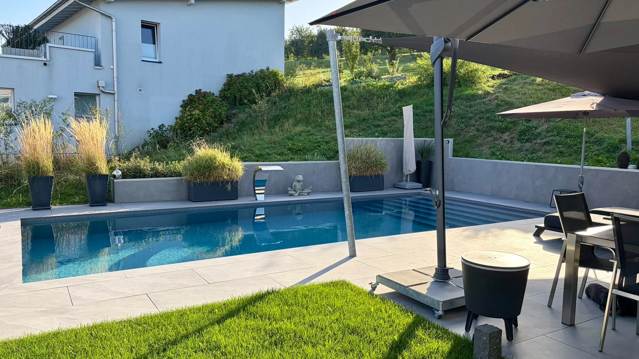 Schwimmbecken mit Einstiegstreppe, Plattenbelag und Bepflanzung