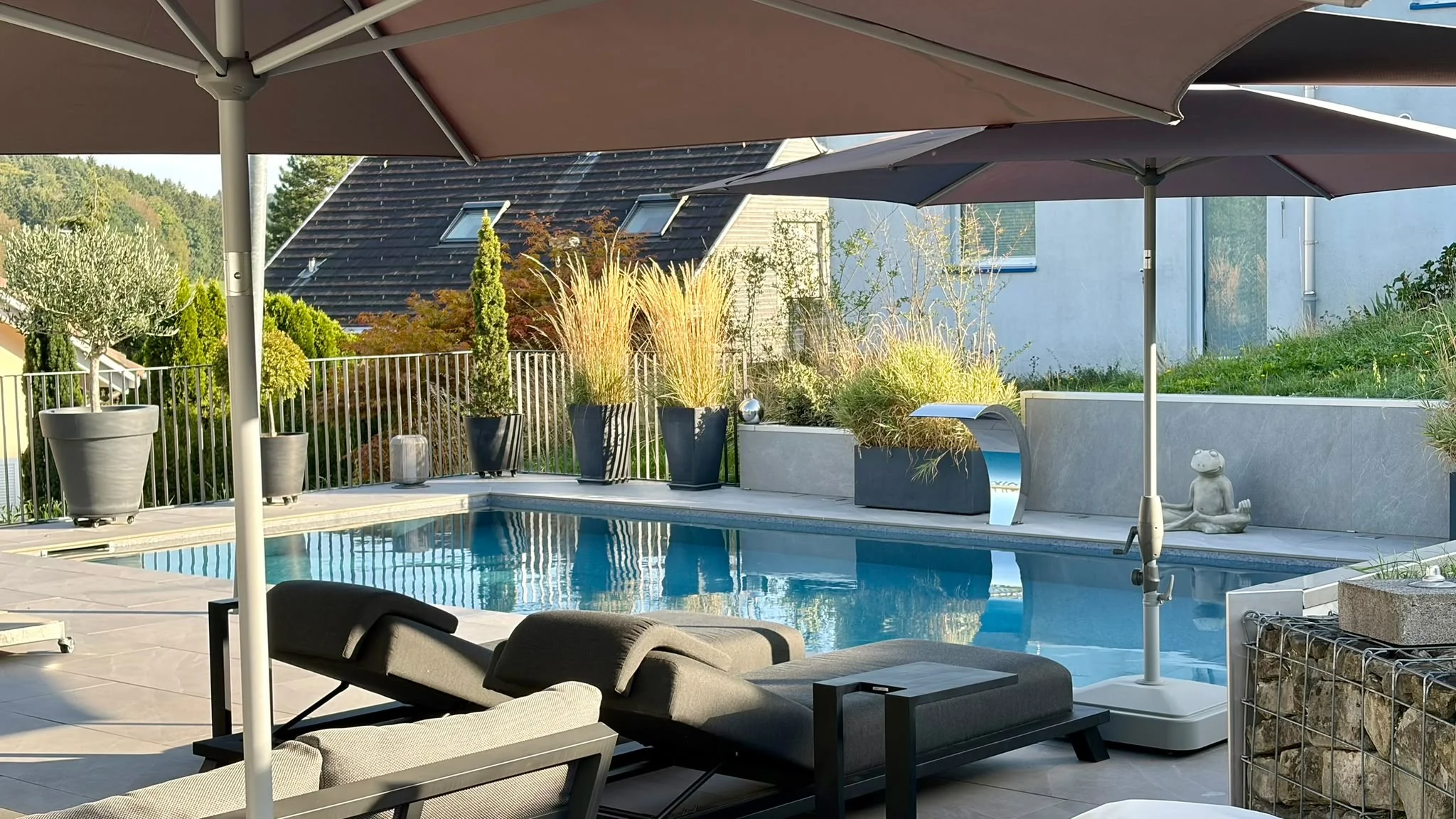 Liegebereich unter Sonnenschirmen mit Blick auf den Pool