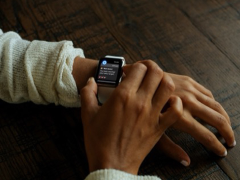 A close up of a person's arms showing a smartwatch on the left wrist with the OnTrack app on display