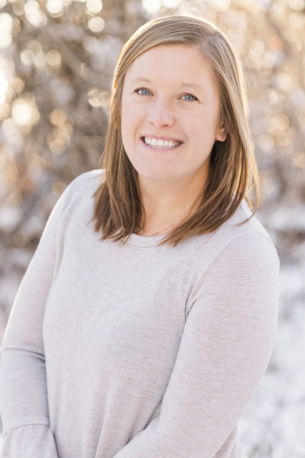 A woman in a beige sweater smiles at the camera.