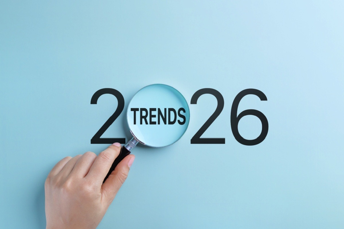 A left hand holds a black magnifying glass over the word, “TRENDS” between the numeral 2 and 2 before 6. 