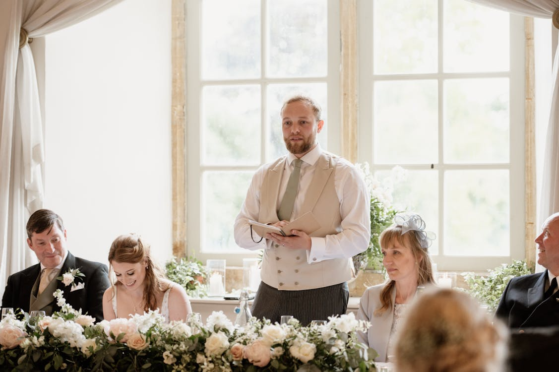 Best friend giving wedding speech during reception at the head table.