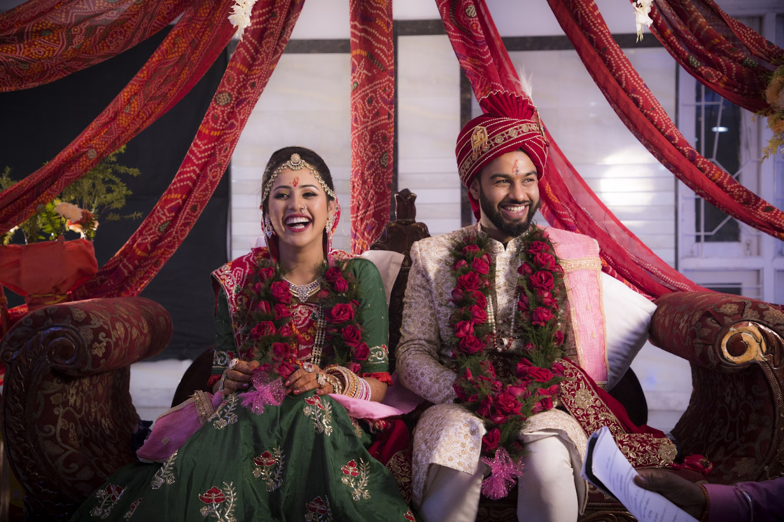 Traditional wedding vows examples – Priya and Aarav smiling during their Indian wedding ceremony in colorful attire and garlands