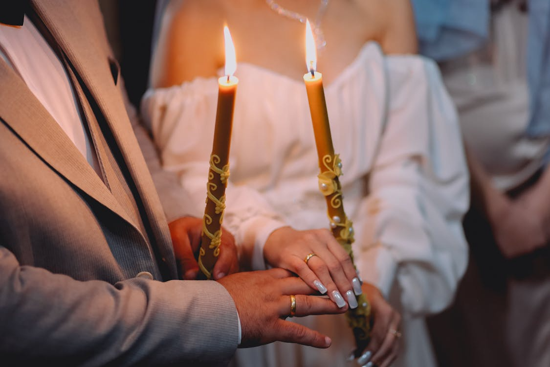 Bride and groom holding unity candles during a traditional wedding ceremony.