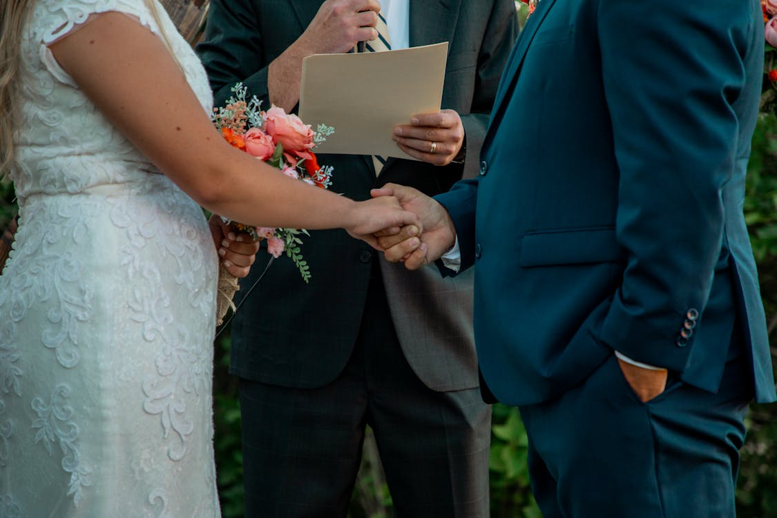 Wedding officiant reading a speech while couple holds hands during ceremony