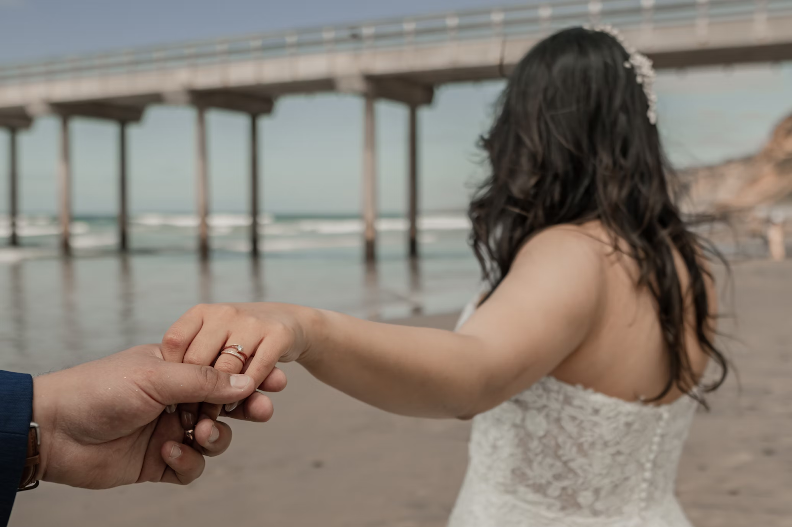 Civil marriage couple holding hands on beach after ceremony